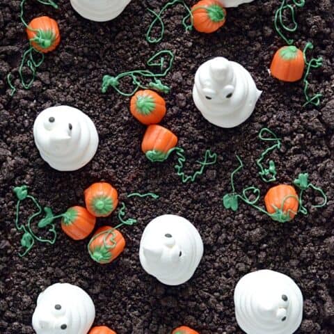 Spooky and cute Halloween cake made with Oreo crumbs, Cool Whip ghosts, and candy corn pumpkins!