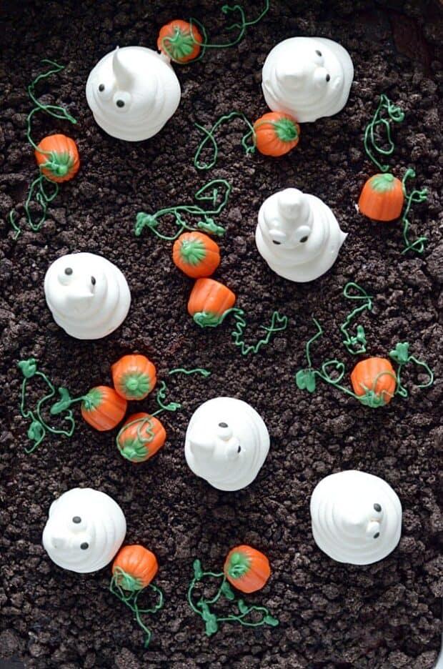 Spooky and cute Halloween cake made with Oreo crumbs, Cool Whip ghosts, and candy corn pumpkins!
